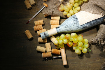 Old bottle of wine, grapes and corks on wooden background