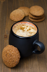 black coffee with foam and oatmeal cookies on the wooden table