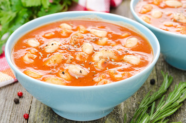 close-up of bowl tomato soup with pasta, white beans, rosemary