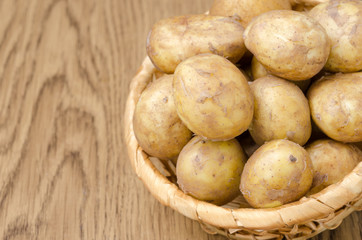 Fototapeta na wymiar new potatoes in a basket on a wooden background