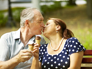 Happy old couple eating ice-cream outdoor.