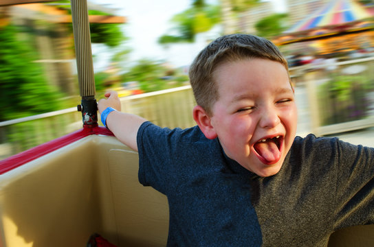 Happy Child Enjoying Spinning Ride At Carnival With Motion Blur 