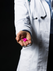 Fototapeta premium Closeup on pills in hand of doctor woman isolated on black