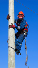Electrician climbs the pole transmission line