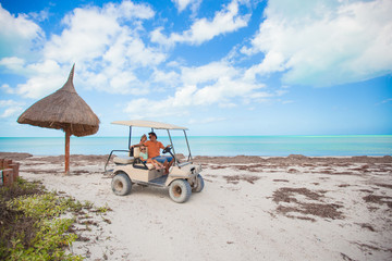 General view golf car with family inside on an exotic beach