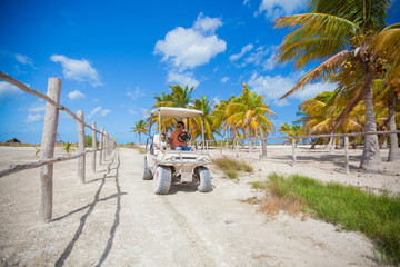 Dad and his two daughters driving golf cart in the palm grove