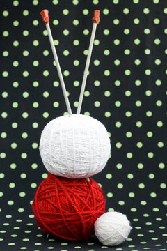 Red and white ball of yarn for knitting and needles