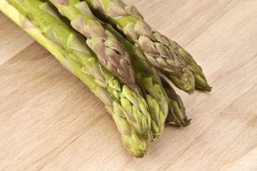 bunch of green asparagus on wooden plate