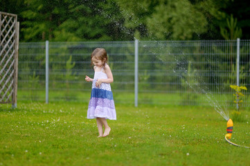 Naklejka premium Girls running though a sprinkler