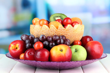 Assortment of juicy fruits on wooden table, on bright