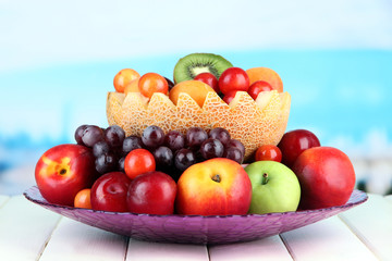 Assortment of juicy fruits on wooden table, on bright