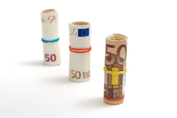 Three descendent rolls of 50 euro bills on white background