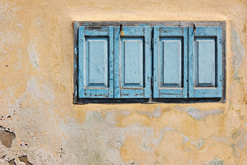 Salmon pink house facade with blue shutters in Fira