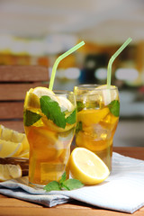 Iced tea with lemon and mint on wooden table, outdoors