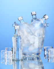 Minibar bottles in bucket with ice cubes,  on blue background
