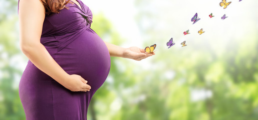 Pregnant woman holding her belly and butterflies on her hand