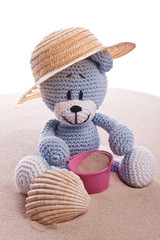 teddy bear with hat and  pink basket on the beach