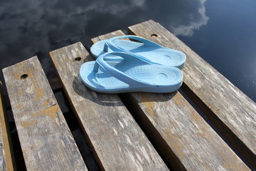 Fototapeta na wymiar beach flip flops on a wooden lake bridge
