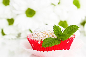 Grosses Minzblatt auf Muffin mit Blumen im Hintergrund