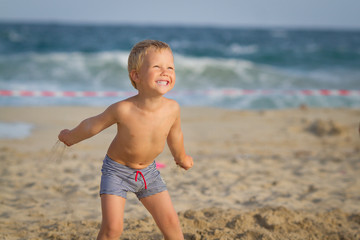 Fototapeta na wymiar Three year old boy playing on the beach with sand