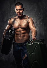 Fototapeta na wymiar Muscular man with two metal fuel cans indoors