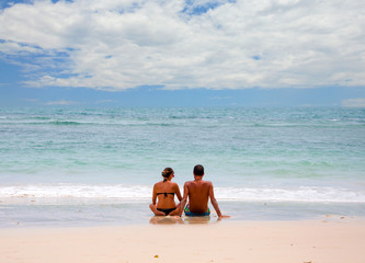 Young happy couple sitting on beach.