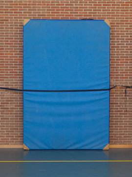 Large Blue Mat Strapped To A Brick Wall