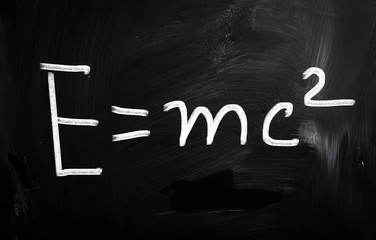 E=mc2 handwritten with white chalk on a blackboard