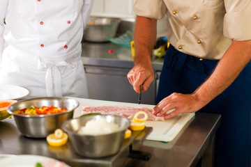 Obraz na płótnie Canvas Chefs preparing fish in restaurant or hotel kitchen