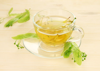 Glass cup of tea with linden on wooden table close-up