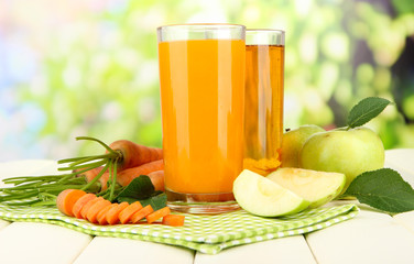 Glasses of juice, apples and carrots