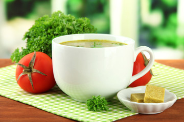 Cup of soup with bouillon cubes on wooden table