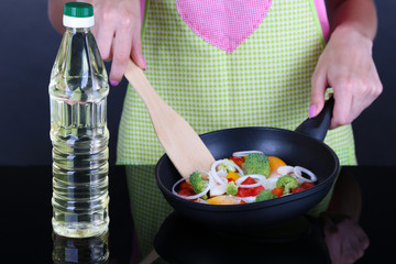 Hands cooking vegetable ragout in pan on gray background