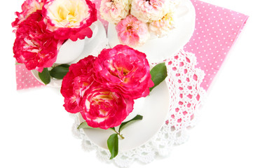 Roses in cups on napkins isolated on white