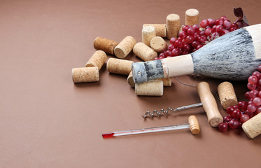 Fototapeta na wymiar Old bottle of wine, grapes and corks on brown background