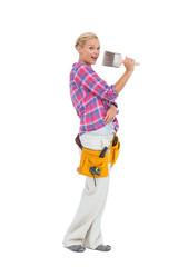 Blonde holding paint brush wearing a tool belt