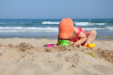 Little girl sitting on sand at beach