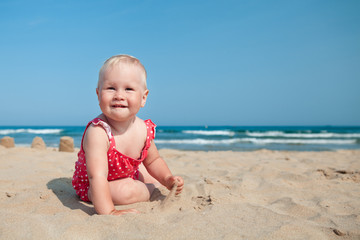 Little girl sitting on sand at beach