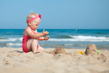 Little girl sitting on sand at beach