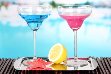 Glasses of cocktails on table near pool