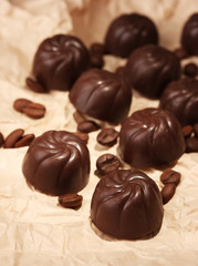 Chocolate candies and coffee beans, on beige paper background