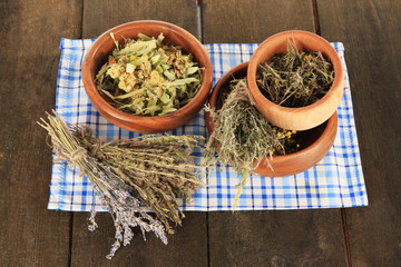 Medicinal Herbs in wooden bowls on napkin on wooden table
