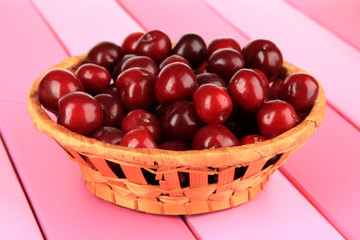 Cherry berries in wicker basket on wooden table close-up