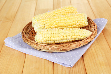 Fresh corn on wicker mat, on wooden background