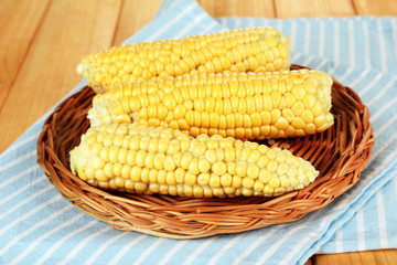 Fresh corn on wicker mat, on wooden background