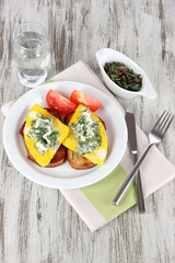 Scrambled eggs and toast on plate on napkin on wooden table