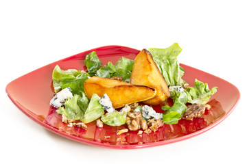 Salad with caramelised pears,walnuts and blue cheese, on red pla
