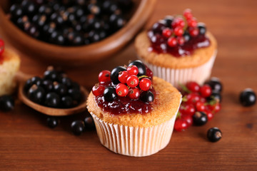 Tasty muffins with berries on wooden table