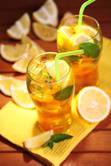 Iced tea with lemon and mint on wooden table, outdoors