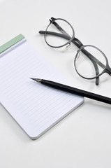 Eye glasses, blank notepad, and mechanical pencil on the table